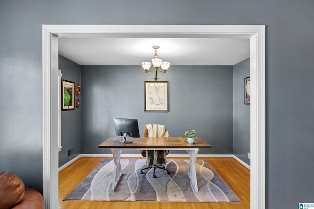 office with baseboards, a chandelier, wood finished floors, and visible vents