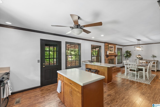 kitchen featuring dark wood-style floors, light countertops, visible vents, ornamental molding, and a center island
