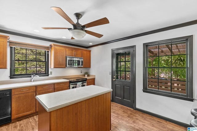 kitchen with light countertops, ornamental molding, a sink, and appliances with stainless steel finishes