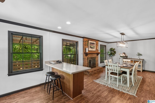 dining area featuring baseboards, ornamental molding, a brick fireplace, dark wood-style floors, and recessed lighting