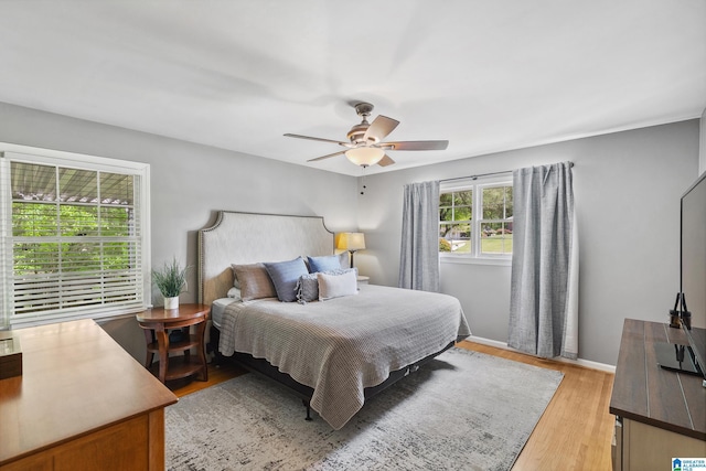 bedroom featuring light wood-type flooring, a ceiling fan, and baseboards