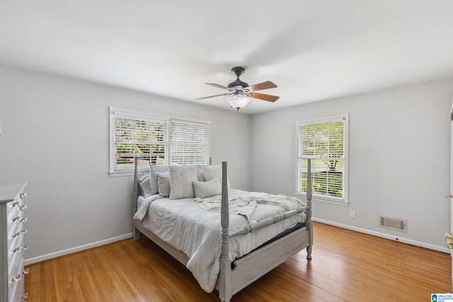 bedroom with baseboards, a ceiling fan, light wood-style floors, and visible vents
