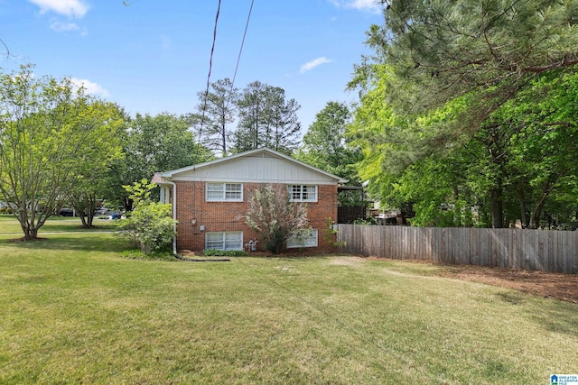 view of property exterior with brick siding, fence, and a yard