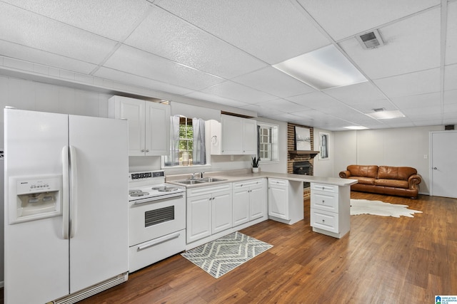 kitchen featuring a sink, open floor plan, white appliances, a peninsula, and a paneled ceiling