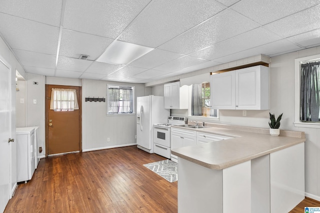 kitchen featuring white appliances, light countertops, a peninsula, dark wood-style flooring, and a paneled ceiling