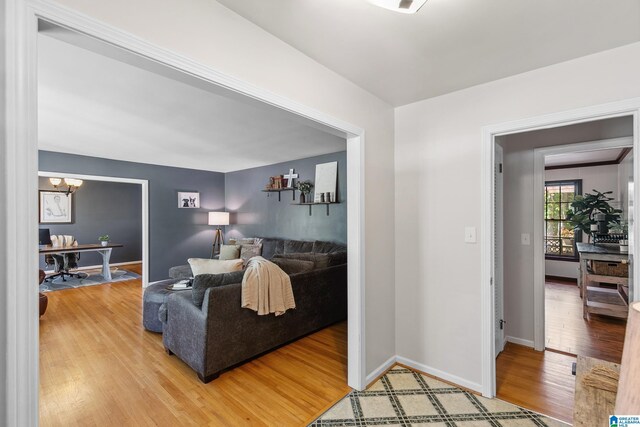 living room with baseboards, a chandelier, and light wood finished floors