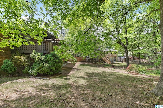 view of yard with fence, a deck, and stairs