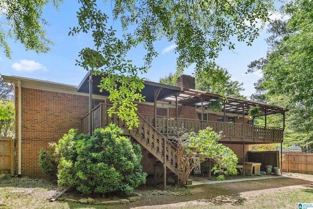 back of property featuring a chimney, fence, brick siding, stairs, and a deck