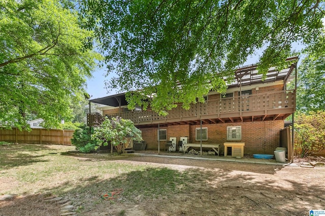 rear view of house with brick siding, fence, and a deck