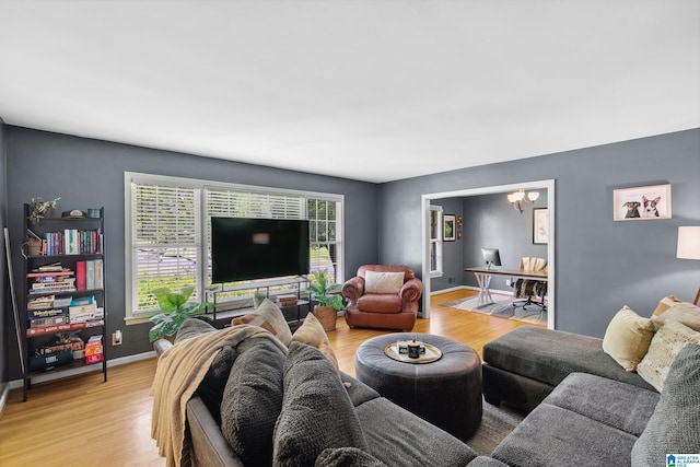 living room featuring light wood finished floors, baseboards, and a notable chandelier
