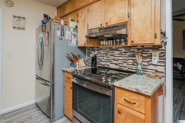 kitchen with light wood finished floors, under cabinet range hood, tasteful backsplash, baseboards, and appliances with stainless steel finishes