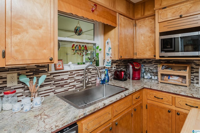 kitchen featuring stainless steel microwave, brown cabinets, decorative backsplash, and a sink