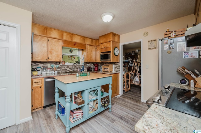 kitchen with backsplash, light wood finished floors, appliances with stainless steel finishes, and light countertops