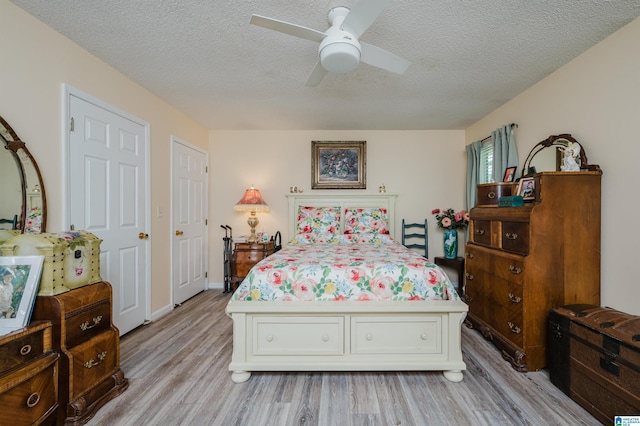 bedroom with a textured ceiling, a ceiling fan, and light wood-style flooring