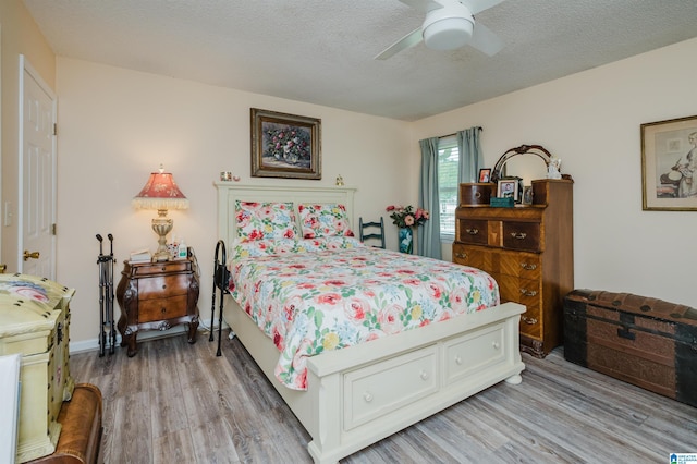 bedroom featuring a textured ceiling, a ceiling fan, and light wood-style flooring