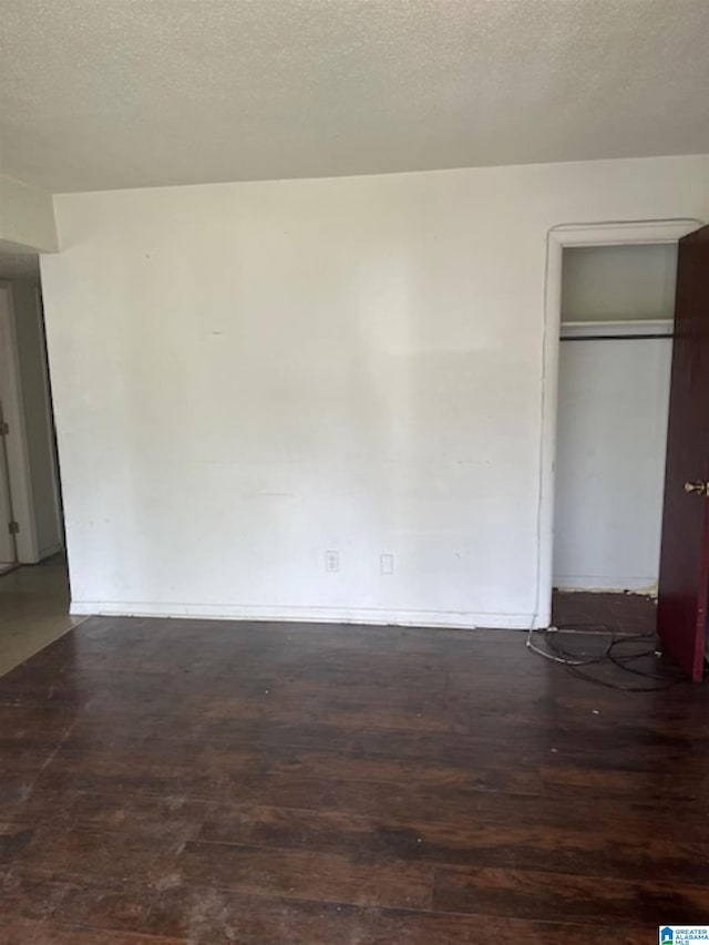 unfurnished bedroom with baseboards, wood finished floors, a textured ceiling, and a closet