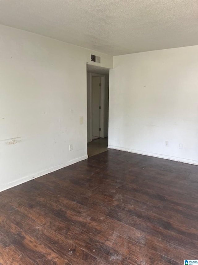 spare room with baseboards, hardwood / wood-style flooring, visible vents, and a textured ceiling