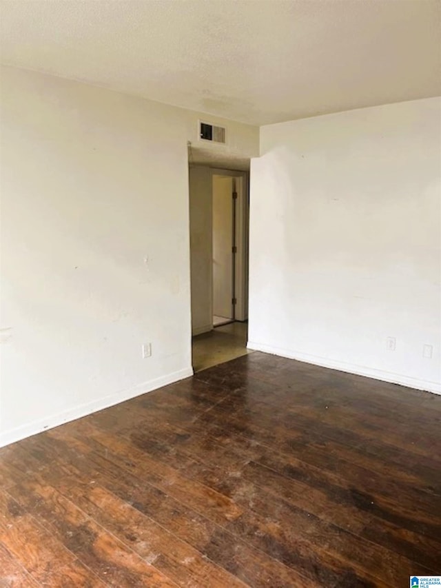 spare room featuring baseboards, hardwood / wood-style flooring, and visible vents