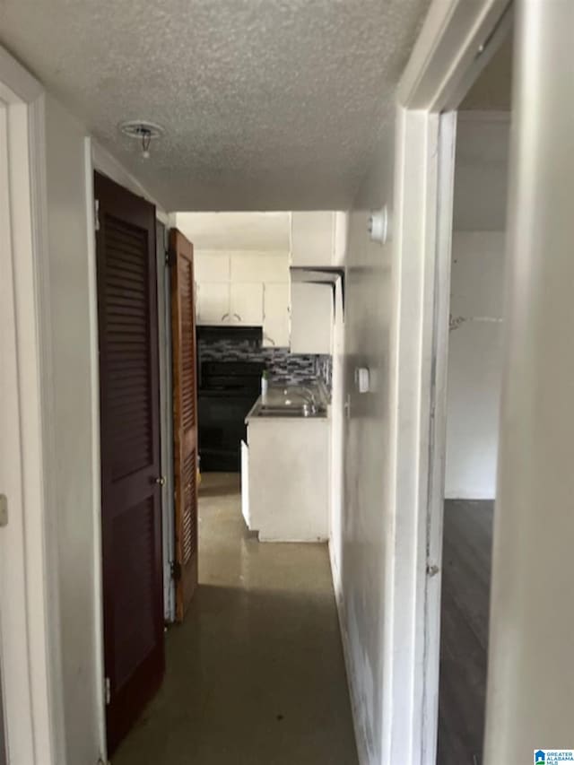 hall with a textured ceiling and finished concrete flooring