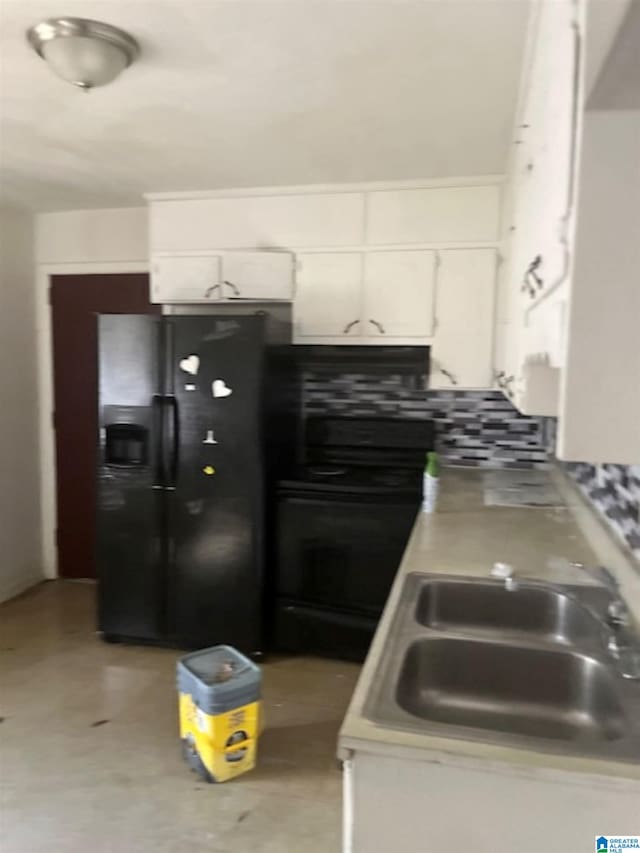 kitchen with light countertops, a sink, white cabinetry, and black fridge