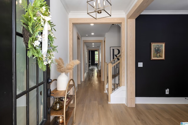 hallway featuring an inviting chandelier, stairway, wood finished floors, and ornamental molding