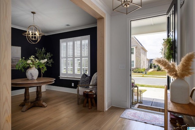 foyer entrance with baseboards, wood finished floors, an inviting chandelier, and ornamental molding
