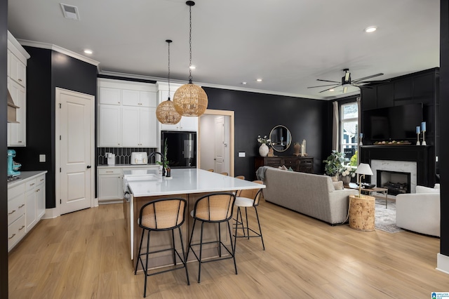 kitchen featuring light wood-style flooring, ornamental molding, black fridge, and a sink