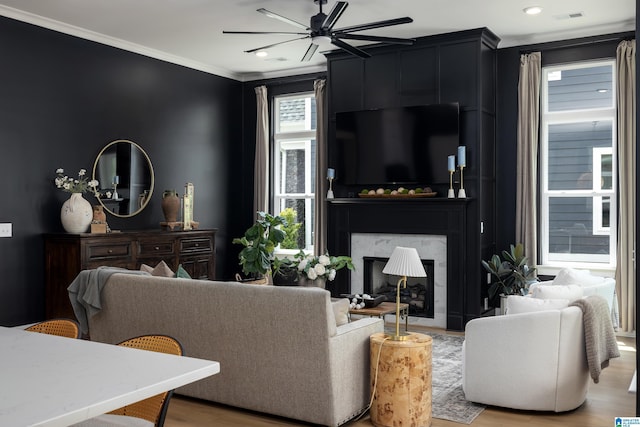 living room with a large fireplace, ceiling fan, crown molding, visible vents, and wood finished floors