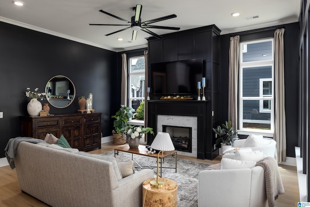 living area with crown molding, recessed lighting, a ceiling fan, and a premium fireplace