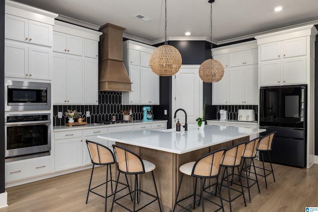 kitchen featuring tasteful backsplash, appliances with stainless steel finishes, light countertops, a kitchen bar, and a sink