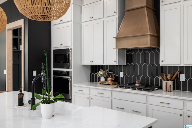 kitchen with custom range hood, appliances with stainless steel finishes, decorative backsplash, and white cabinetry