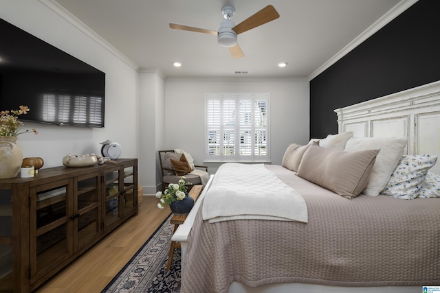 bedroom featuring visible vents, ornamental molding, a ceiling fan, and light wood-style flooring