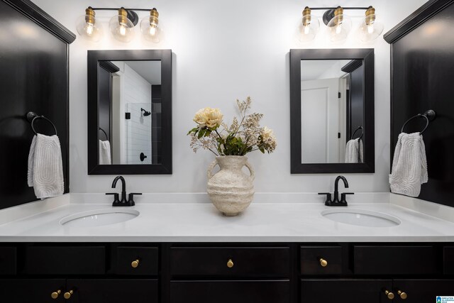full bath featuring a tile shower, double vanity, and a sink