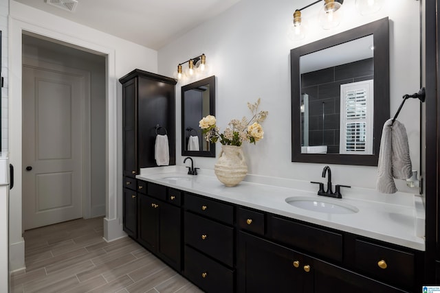 full bathroom with double vanity, wood finished floors, visible vents, and a sink