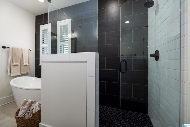 bathroom with baseboards, a freestanding bath, and tiled shower