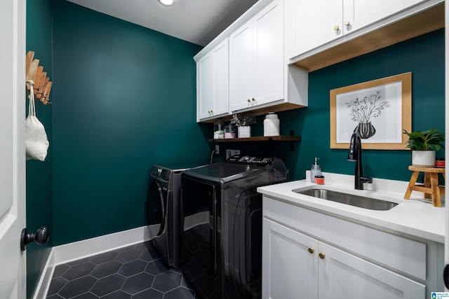 washroom featuring dark tile patterned flooring, separate washer and dryer, cabinet space, a sink, and baseboards