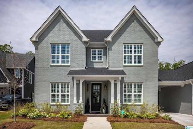 view of front facade with a shingled roof and brick siding