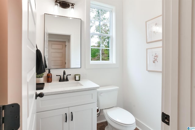 half bathroom featuring baseboards, vanity, and toilet