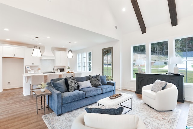 living room featuring beamed ceiling, recessed lighting, light wood-style floors, and a healthy amount of sunlight