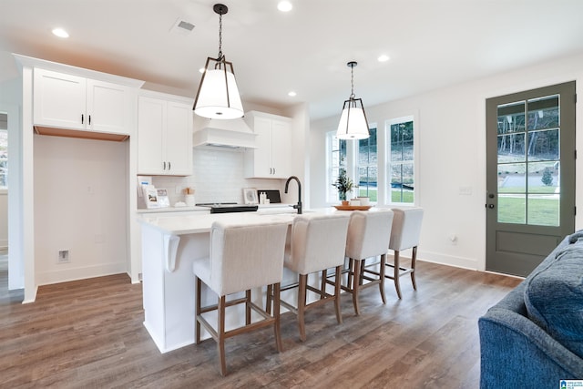 kitchen with white cabinets, open floor plan, light countertops, premium range hood, and backsplash