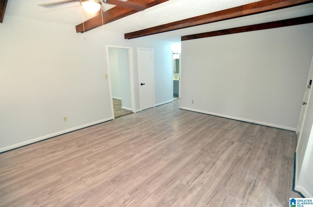 empty room with baseboards, ceiling fan, wood finished floors, and beamed ceiling