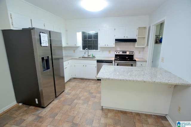 kitchen featuring backsplash, stone finish flooring, appliances with stainless steel finishes, a sink, and white cabinetry