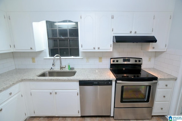 kitchen featuring under cabinet range hood, stainless steel appliances, white cabinets, and a sink