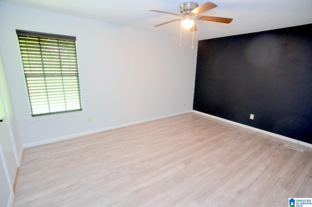 spare room with light wood-style floors, baseboards, a ceiling fan, and a wealth of natural light