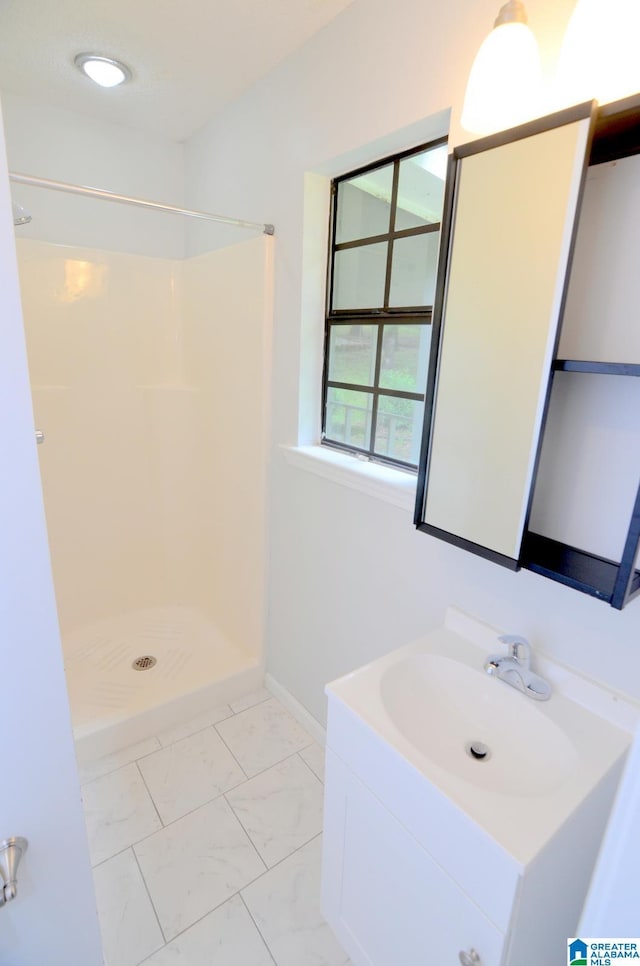 bathroom featuring vanity, baseboards, walk in shower, and marble finish floor