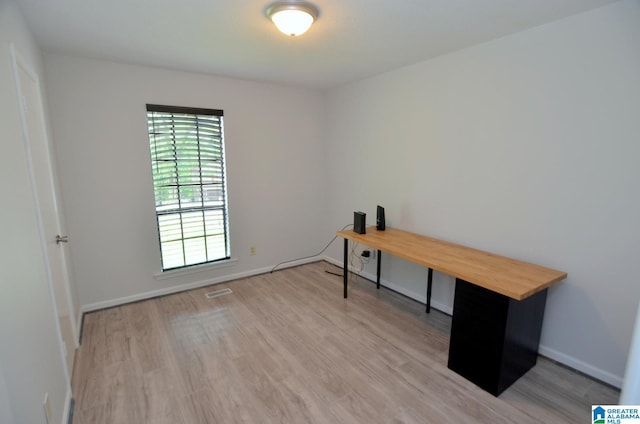 unfurnished office featuring baseboards, wood finished floors, and visible vents