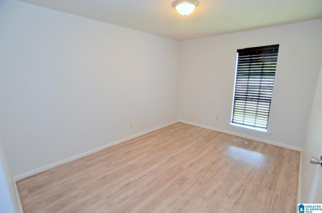 spare room featuring baseboards, light wood finished floors, and visible vents