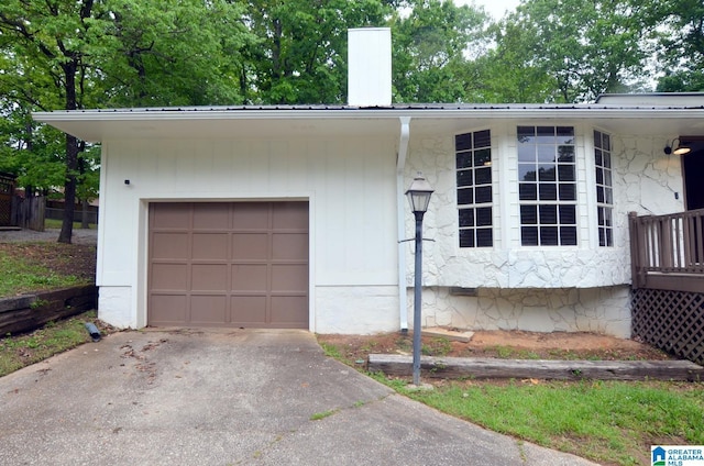 exterior space with a chimney, driveway, metal roof, and a garage
