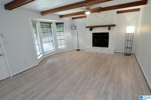 unfurnished living room with a ceiling fan, a fireplace, beam ceiling, wood finished floors, and baseboards
