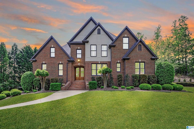 view of front of house featuring board and batten siding, a yard, french doors, and brick siding